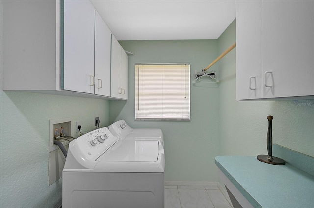 laundry area featuring washer and clothes dryer, light tile patterned floors, and cabinets