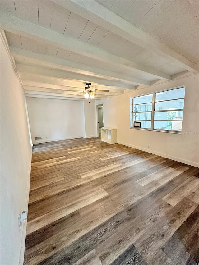 empty room with beamed ceiling, hardwood / wood-style flooring, and ceiling fan