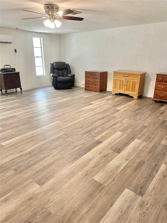 unfurnished room featuring a textured ceiling, light hardwood / wood-style flooring, ceiling fan, and a wall unit AC