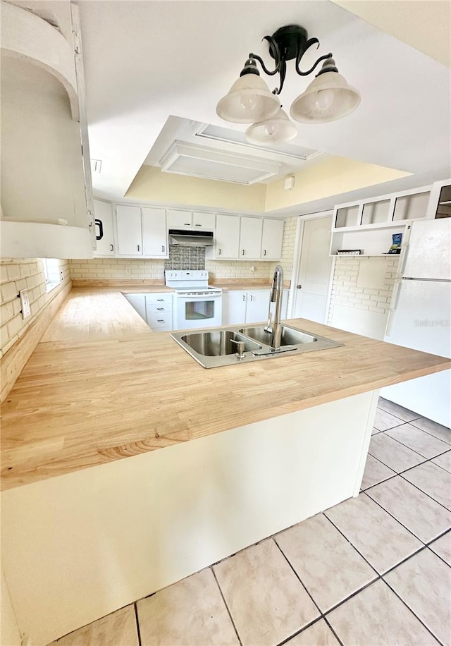 kitchen featuring kitchen peninsula, light tile patterned floors, white appliances, and white cabinetry