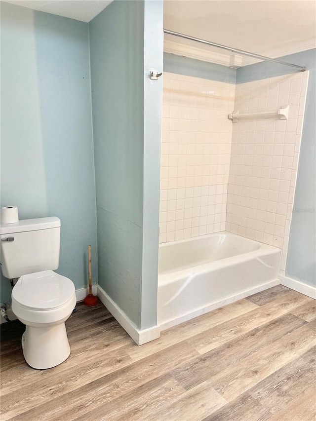 bathroom with toilet, hardwood / wood-style flooring, and tiled shower / bath