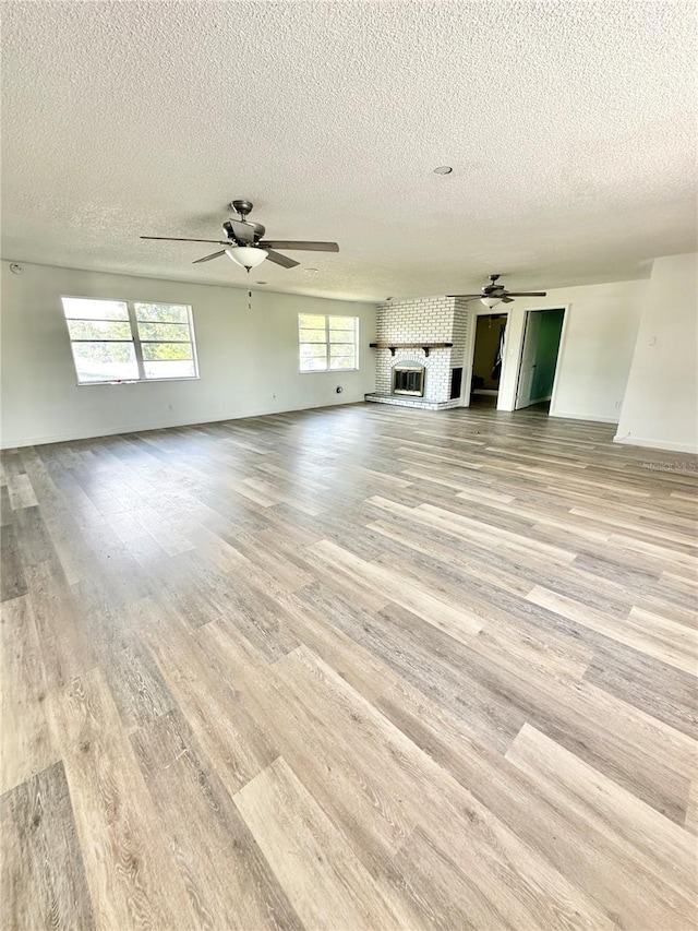 unfurnished living room featuring light hardwood / wood-style flooring, a large fireplace, and a textured ceiling