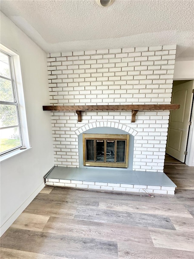 interior details with a textured ceiling, a brick fireplace, and wood-type flooring