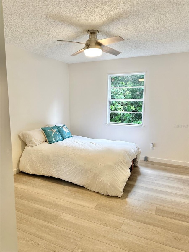 bedroom featuring a textured ceiling, ceiling fan, and light hardwood / wood-style floors