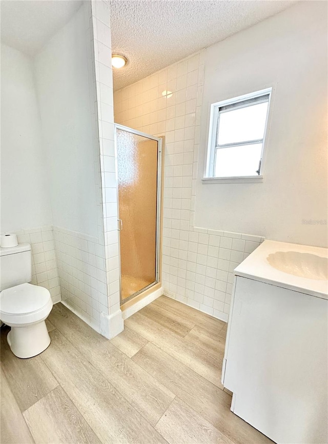 bathroom with a shower with door, tile walls, and toilet