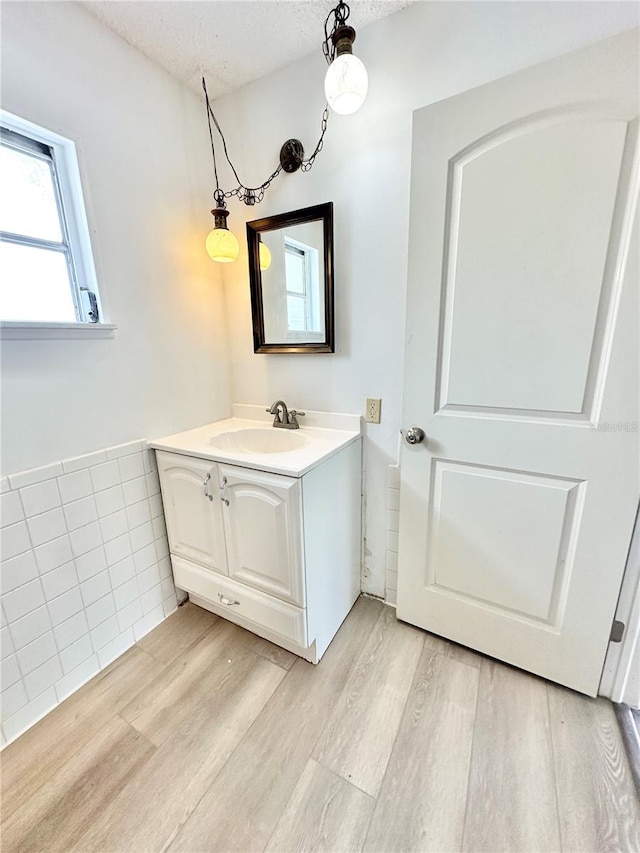 bathroom with a textured ceiling, vanity, hardwood / wood-style floors, and tile walls