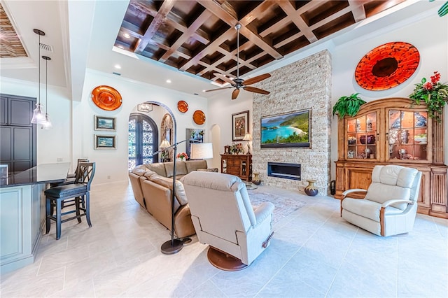 living room featuring a high ceiling, a fireplace, beamed ceiling, coffered ceiling, and ceiling fan