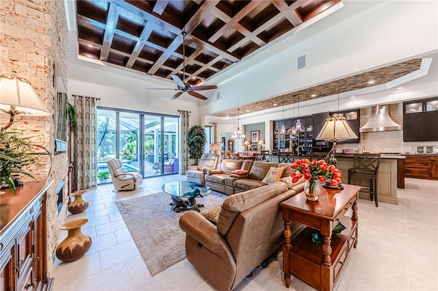 living room with a high ceiling, beam ceiling, coffered ceiling, and ceiling fan