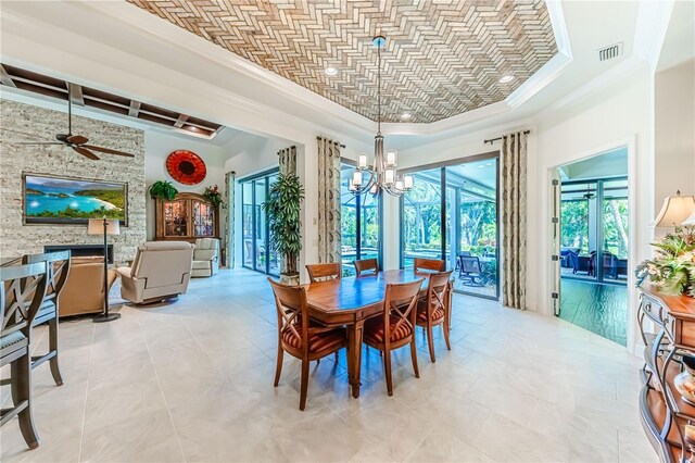 dining space featuring ceiling fan with notable chandelier, plenty of natural light, a tray ceiling, and light tile patterned floors