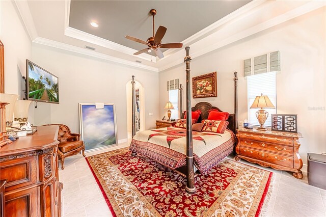 bedroom featuring ceiling fan, a raised ceiling, light tile patterned floors, and multiple windows