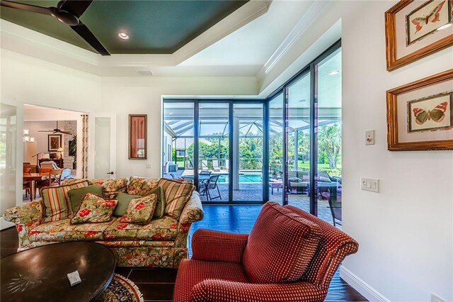 living room featuring ceiling fan, dark hardwood / wood-style floors, a tray ceiling, and ornamental molding