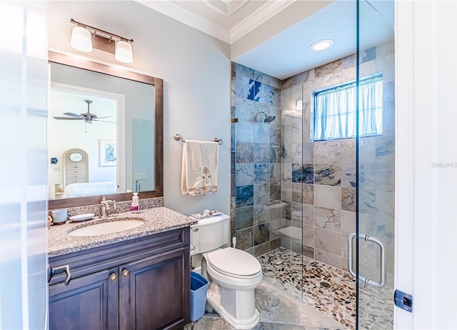 bathroom featuring ceiling fan, a shower with door, toilet, vanity, and ornamental molding