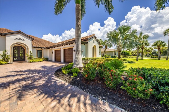 mediterranean / spanish house featuring a garage and a front lawn