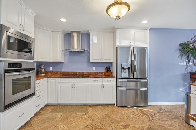 kitchen featuring white cabinetry, stainless steel appliances, and wall chimney range hood