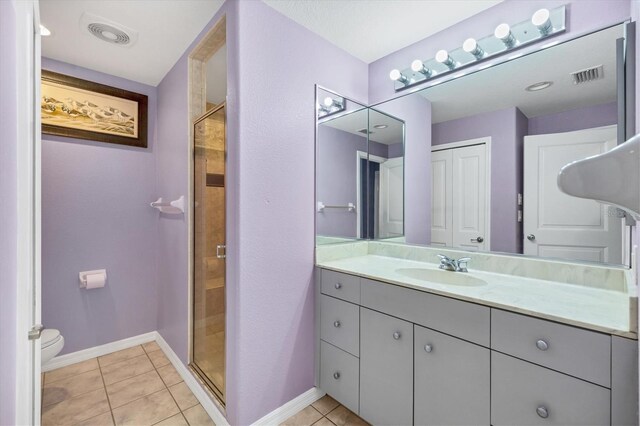 bathroom featuring tile patterned flooring, a shower with door, vanity, and toilet