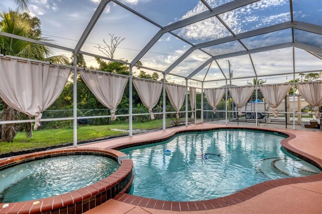 view of pool featuring glass enclosure, an in ground hot tub, and a patio area