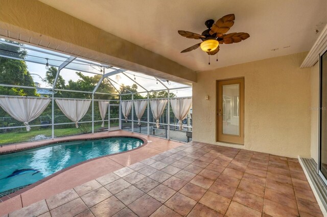 view of pool featuring a patio, glass enclosure, and ceiling fan