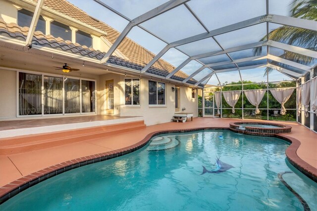 view of swimming pool with glass enclosure, ceiling fan, an in ground hot tub, and a patio