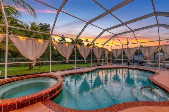 pool at dusk with a patio area, an in ground hot tub, and a lanai