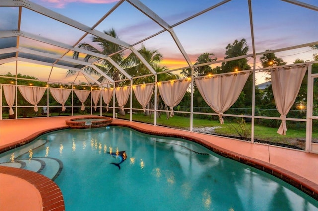 pool at dusk featuring glass enclosure and an in ground hot tub