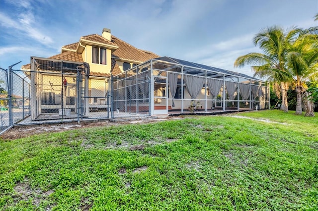 rear view of house featuring glass enclosure and a lawn