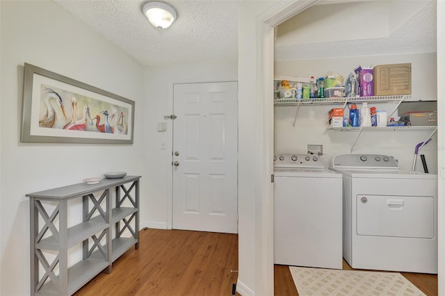 washroom featuring a textured ceiling, hardwood / wood-style flooring, and washer and dryer