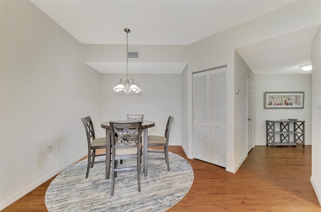 dining area with hardwood / wood-style floors and a chandelier