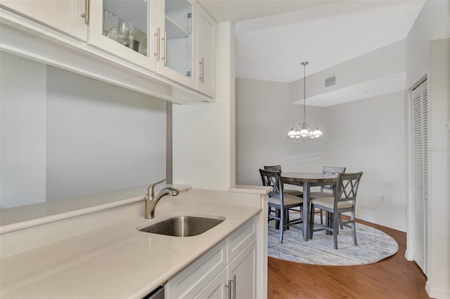 kitchen featuring sink, a notable chandelier, white cabinetry, and light hardwood / wood-style floors