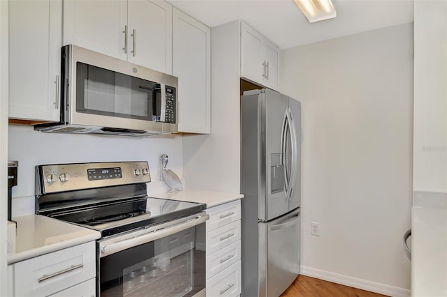 kitchen with white cabinets, light wood-type flooring, and stainless steel appliances