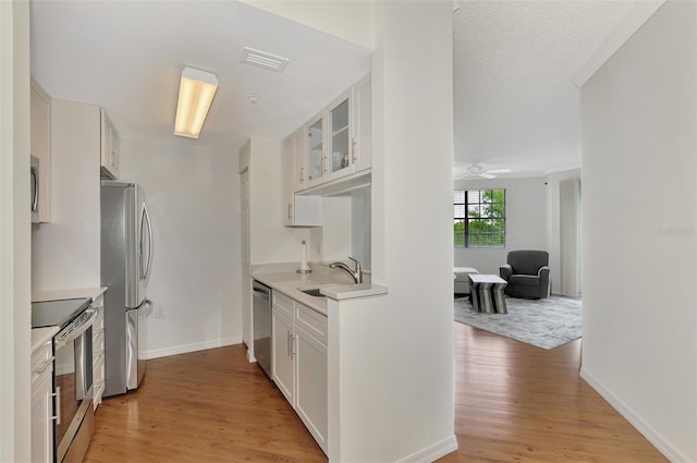 kitchen with ceiling fan, white cabinets, light hardwood / wood-style floors, sink, and stainless steel appliances