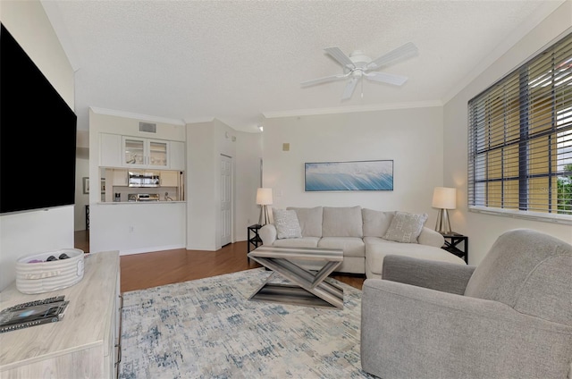 living room with a textured ceiling, ceiling fan, crown molding, and hardwood / wood-style flooring