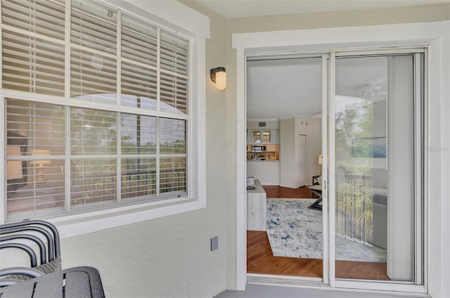 entryway with crown molding, a healthy amount of sunlight, and wood-type flooring