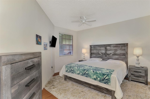 bedroom with a textured ceiling, ceiling fan, and hardwood / wood-style flooring