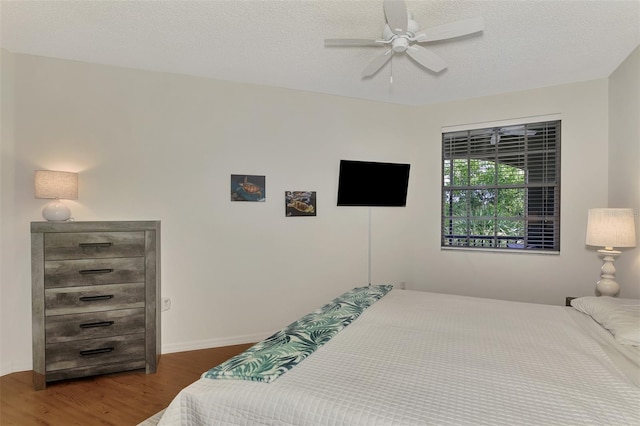 bedroom with ceiling fan, a textured ceiling, and dark hardwood / wood-style flooring