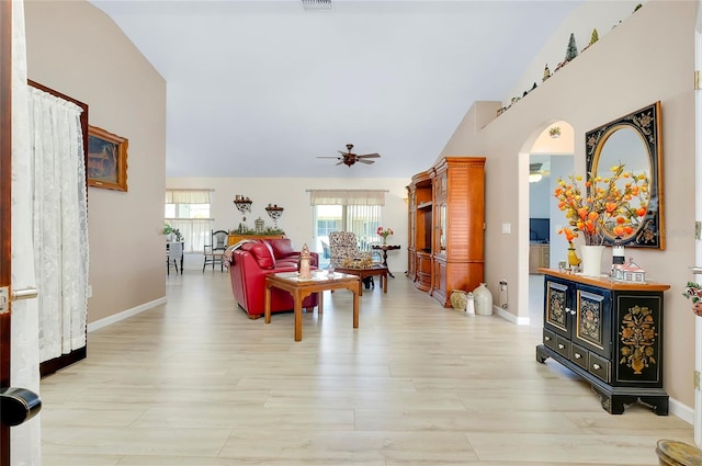 living room with ceiling fan, vaulted ceiling, and light wood-type flooring