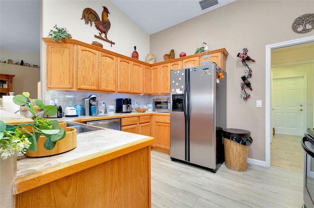 kitchen featuring appliances with stainless steel finishes, vaulted ceiling, kitchen peninsula, and decorative backsplash