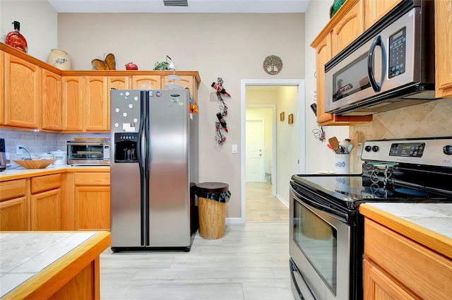 kitchen featuring appliances with stainless steel finishes, tile counters, and backsplash