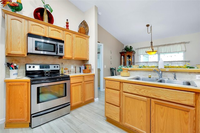 kitchen featuring appliances with stainless steel finishes, light hardwood / wood-style flooring, backsplash, sink, and lofted ceiling