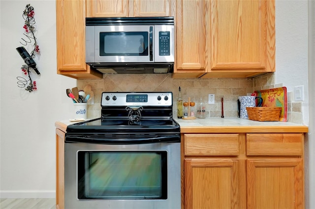 kitchen featuring tasteful backsplash, light hardwood / wood-style flooring, and stainless steel appliances