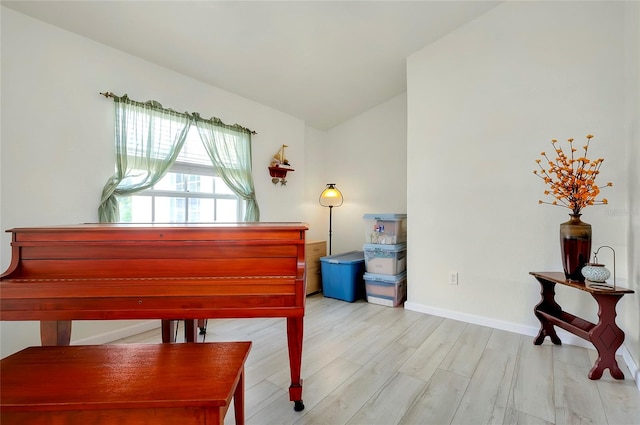 miscellaneous room with light hardwood / wood-style floors and vaulted ceiling