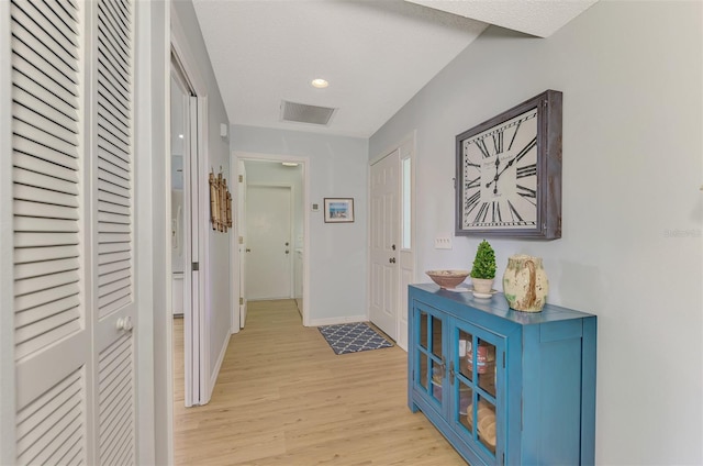 hallway featuring light wood-type flooring and a textured ceiling