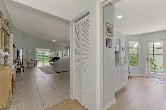 corridor with light hardwood / wood-style floors and lofted ceiling