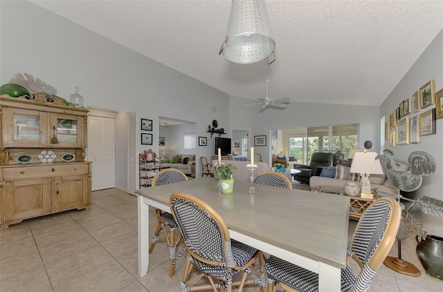 dining area with ceiling fan, light tile patterned floors, vaulted ceiling, and a textured ceiling