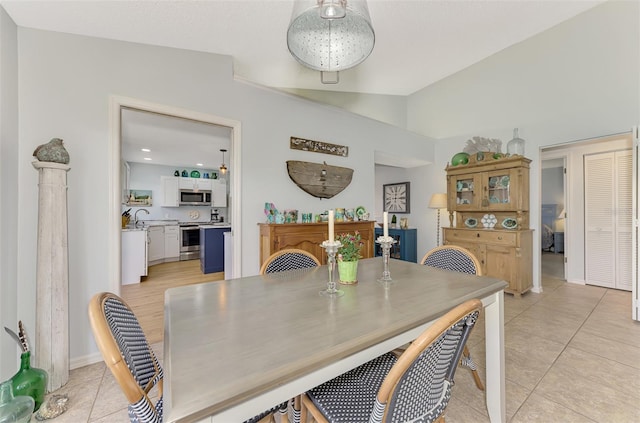 dining room with vaulted ceiling, sink, and light tile patterned floors