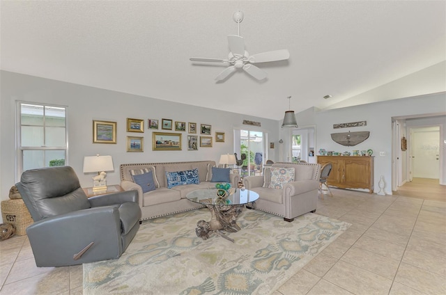 tiled living room featuring ceiling fan, vaulted ceiling, and a textured ceiling