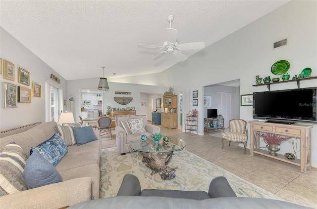 living room featuring a textured ceiling, vaulted ceiling, ceiling fan, and light tile patterned floors