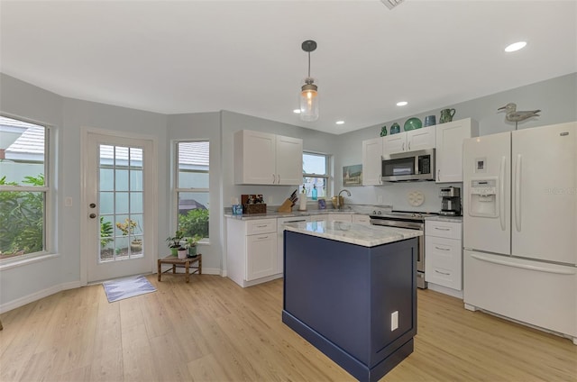 kitchen featuring appliances with stainless steel finishes, white cabinets, a center island, and decorative light fixtures