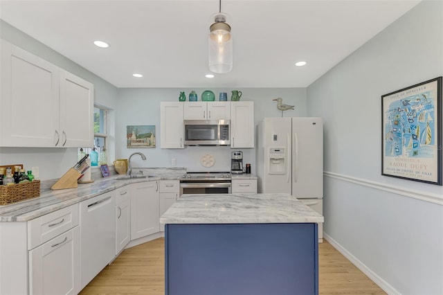 kitchen featuring stainless steel appliances, a center island, decorative light fixtures, sink, and white cabinets