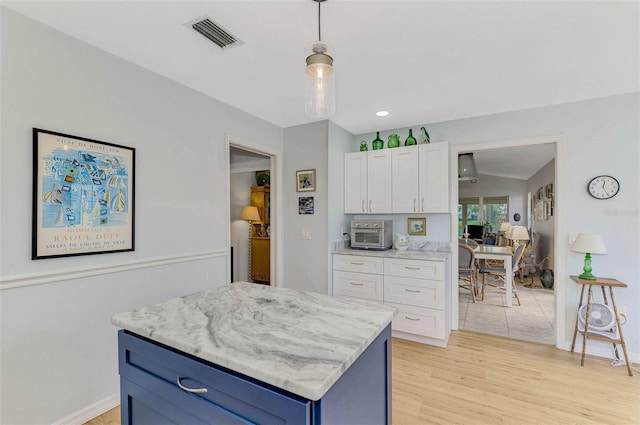 kitchen with blue cabinetry, white cabinets, light hardwood / wood-style floors, pendant lighting, and a center island