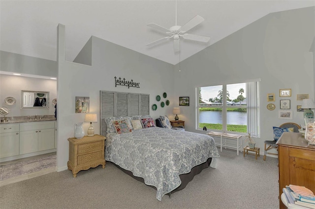 carpeted bedroom with a water view, sink, high vaulted ceiling, and ensuite bath